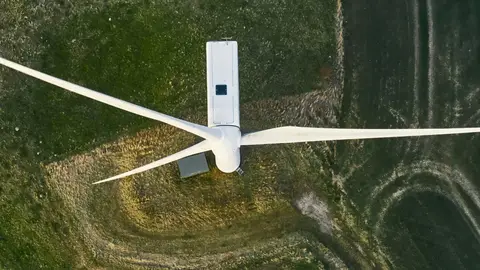 Windkraftanlage aus der Luft mit umliegender Grünfläche.